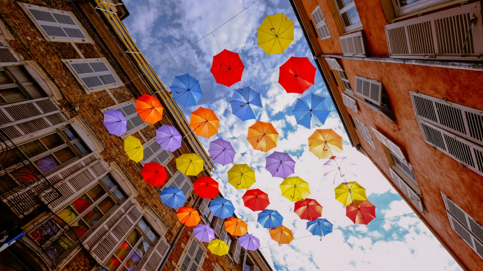 Création et suivi de sites internet Des parapluies colorés suspendus dans une rue de Mâcon