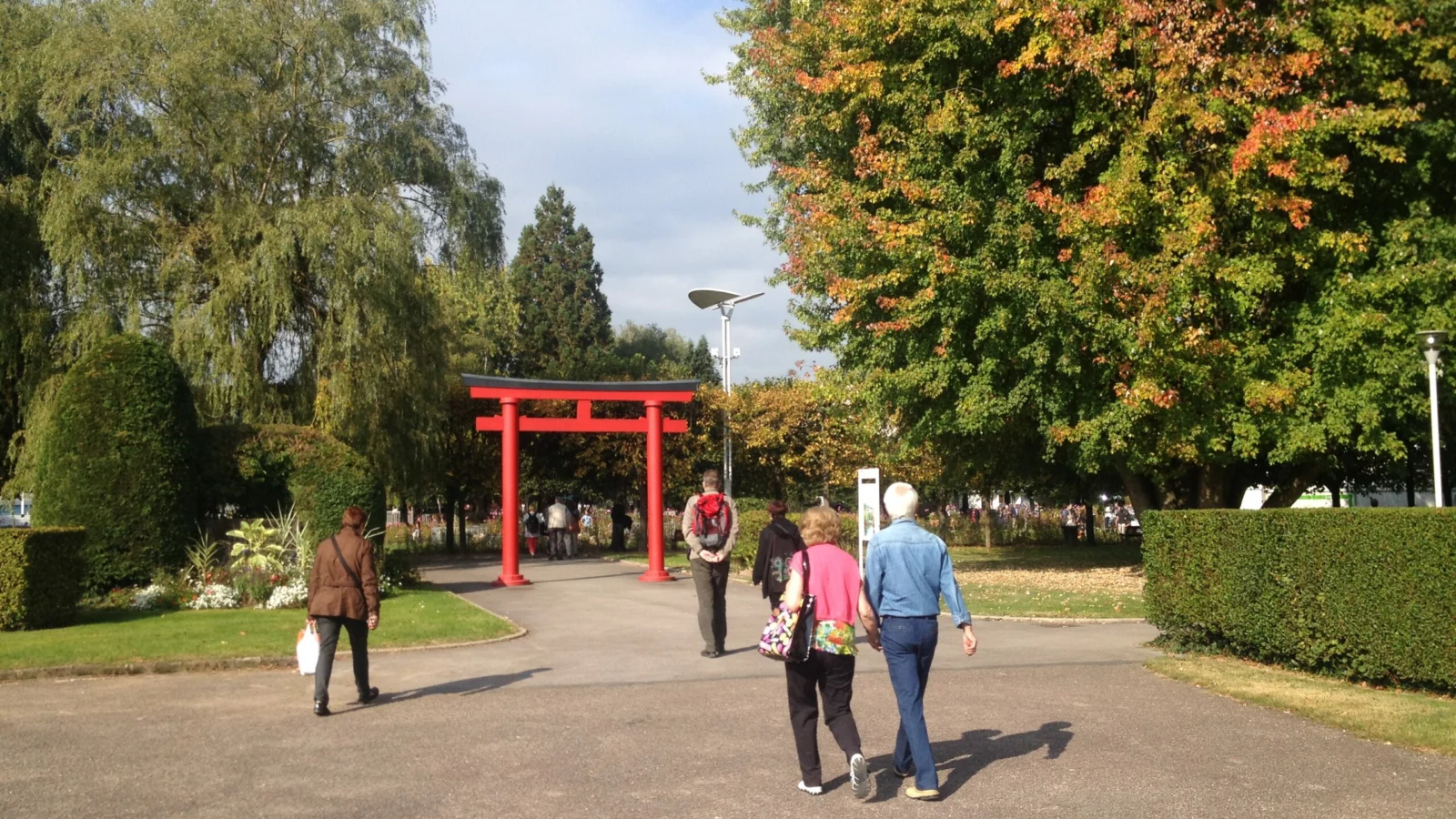Accompagnement des entreprises Une allée arborée et un portique rouge dans un parc de Saint-Dié-des-Vosges